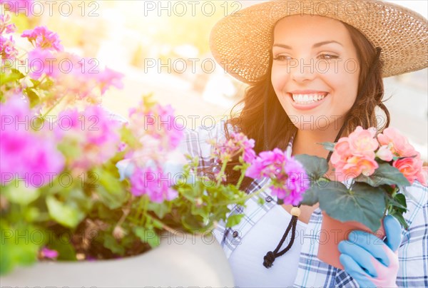 Happy young adult woman wearing hat and gloves gardening outdoors