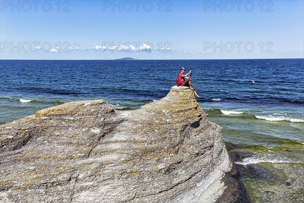 Hiker sitting on limestone pillar photographing landscape
