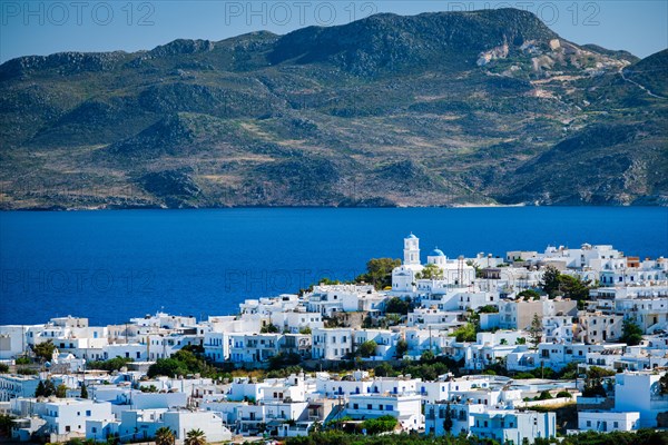 View of Plaka village with traditional Greek church and white painted houses and ocean coast