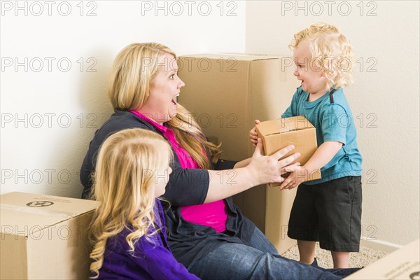 Playful young family in empty room playing with moving boxes