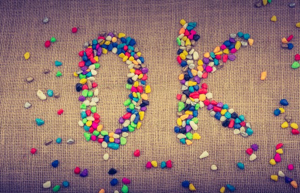 Colorful pebbles form the word OK on canvas ground