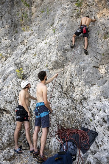 Young man belays a climber on lead