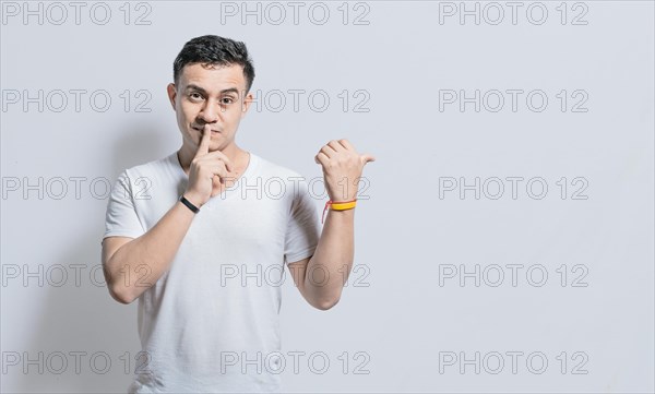 Handsome man with finger on lip pointing to the side on isolated background