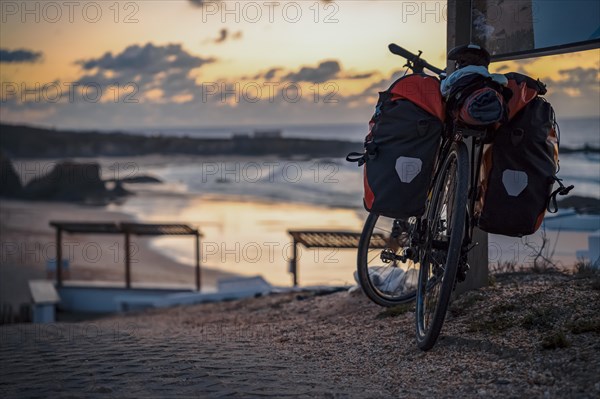 Bicycle with bags by the Almograve beach at sunset