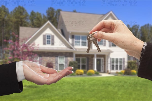 Real estate agent handing over the house keys in front of a beautiful new home