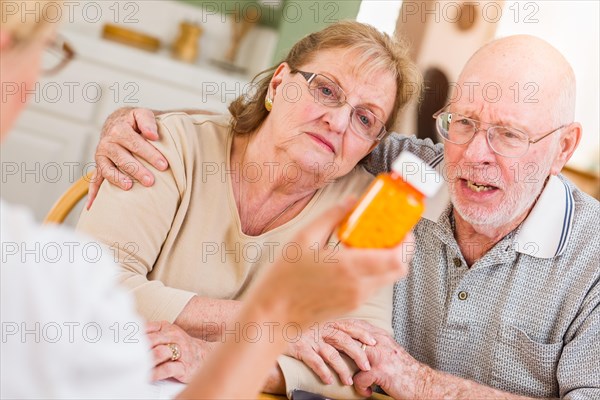 Doctor or nurse explaining prescription medicine to senior adult couple