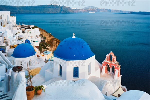 Famous view from viewpoint of Santorini Oia village with blue dome of whitewashed greek orthodox Christian church of traditional greek architecture