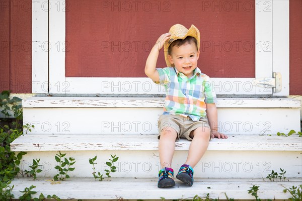 Young mixed-race chinese and caucasian boy wearing cowboy hat relaxing on the steps