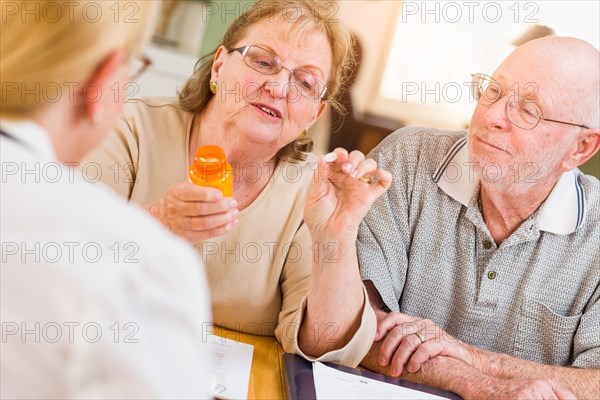 Doctor or nurse explaining prescription medicine to senior adult couple