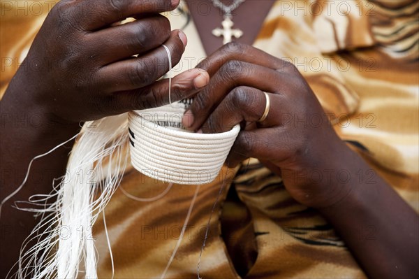 Close-up of a lady weaving a traditional basket at the Ladies' Cooperative