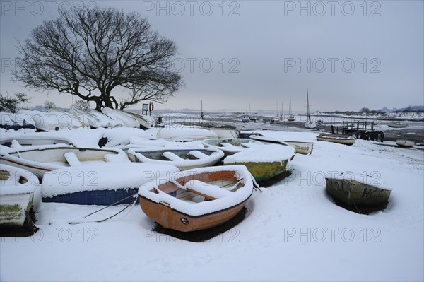 Snow covered boats moored at the edge of the mudflats