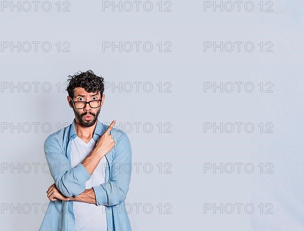 Surprised person pointing an advertisement to the right, Amazed handsome man pointing his finger to the right