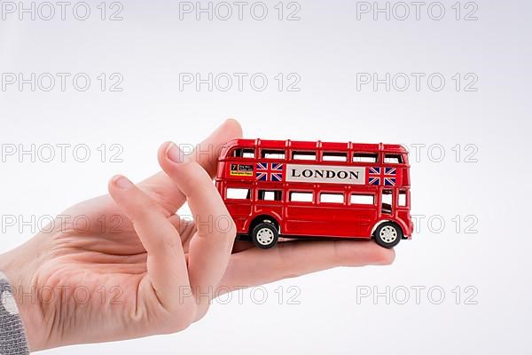 Hand holding a London double decker bus on a white background,
