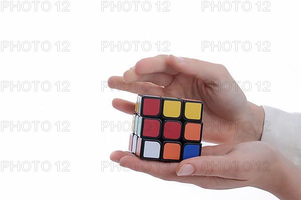 Child holding a Rubik's cube in hand on a white background,