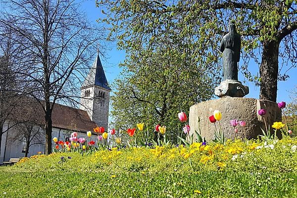 St. Michael's Church and the war memorial in the centre of Peiting. Tulips in the foreground. Bavaria, Germany