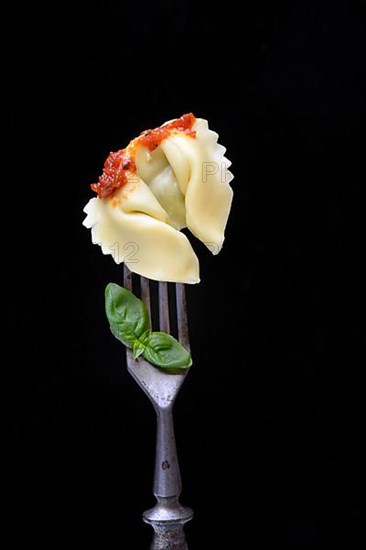 A tortelloni with tomato sauce on a fork, pasta