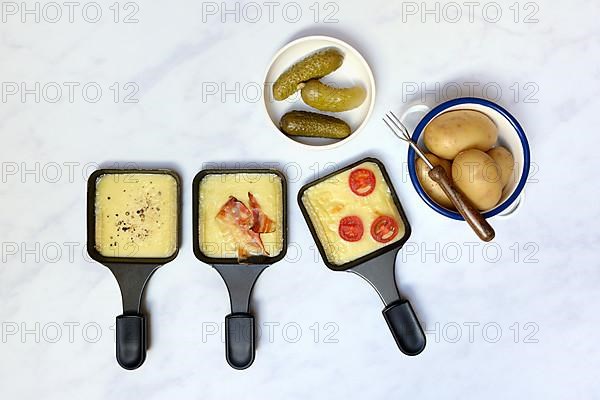 Raclette, melted raclette cheese in pans and ingredients