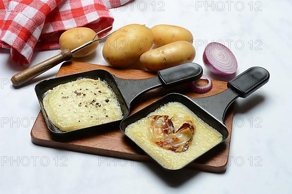 Raclette, melted raclette cheese in pans and ingredients