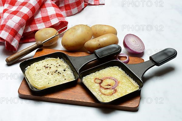 Raclette, melted raclette cheese in pans and ingredients