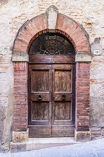 Weathered old round arch front door, Motepulciano