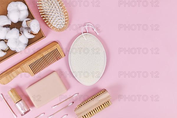 Eco friendly wooden beauty and hygiene products like comb and soap on pink background,