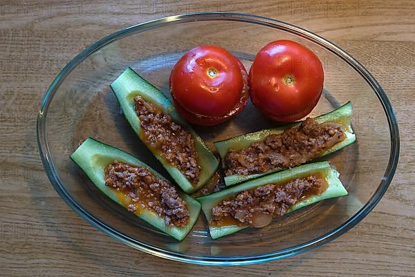 Stuffed peppers and tomatoes in a glass casserole on a wooden table, Bavaria