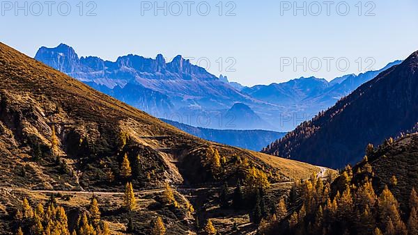 Hiking trail in autumnal mountain landscape, the mountain backdrop of the Dolomites in the background