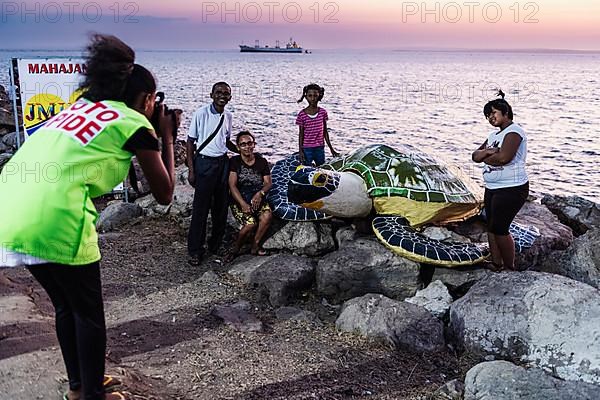 Photographer, photographs family with artificial turtle