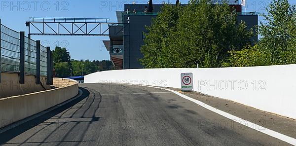 View from racing car perspective of racing driver on entrance of pit lane with sign traffic speed limit 60 km/h