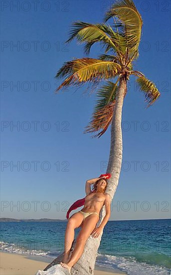 Woman leaning against coconut palm
