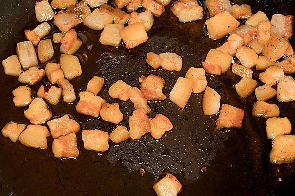 Pancetta cubes are fried in a pan