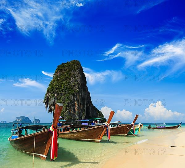 Long tail boat on tropical beach with limestone rock