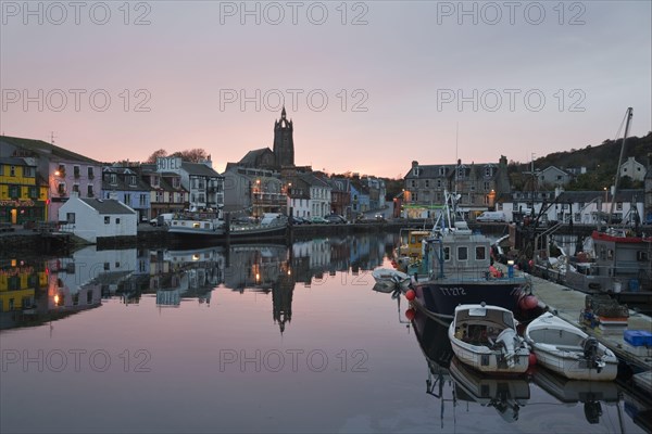 Boats moored in town harbour at sunset