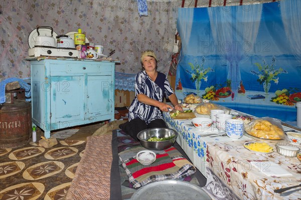 Kazakh nomad woman prepares the table for guests in a yurt