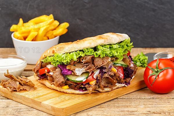 Doener Kebab Doner Kebap fast food meal in pita bread menu with fries on wooden board in Stuttgart