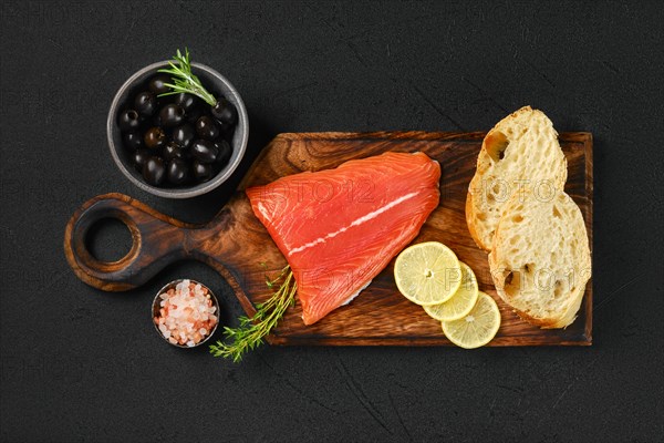 Top view of piece of fresh salmon tail fillet with ciabatta and spicy herb sauce