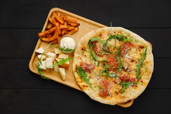 Top view of focaccia with tomato and parmesan served with cheese and fried sweet potato on wooden tray