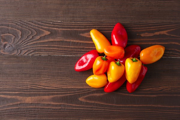 Sweet mini peppers sorted by color natural wooden background