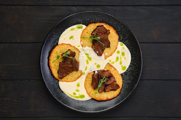 Top view of potato fritters with with fried beef slices