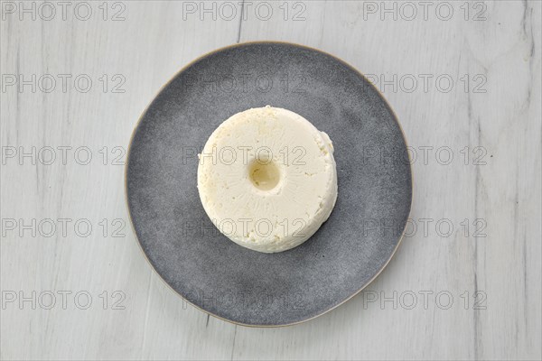 Top view of pressed cottage curd cheese on ceramic plate