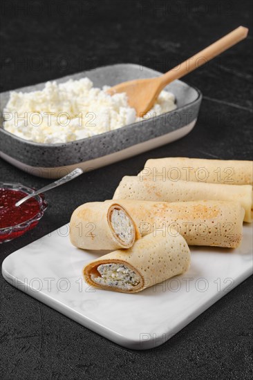 Homemade pancakes stuffed with cottage cheese on marble serving plate