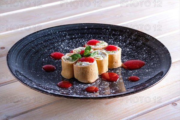 Pancakes stuffed with curd and kiwi decorated with strawberry jam