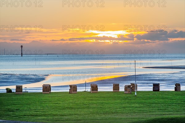Grassy beach with beach chairs at sunset on the Wadden Sea at the mouth of the Weser