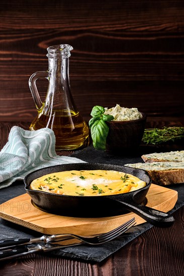 Omelette in cast iron skillet with bread and herbal butter