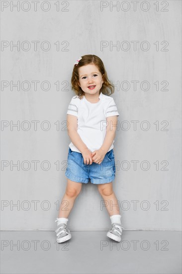 Two years old girl in white t-short and jeans shorts posing in studio