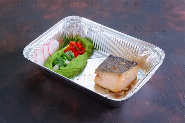 Fried salmon with pea mash decorated with radish and peas in take away packaging