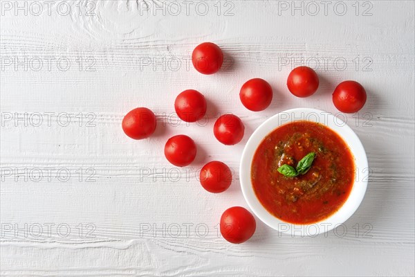 Gazpacho cold summer tomato soup with basil in a bowl on bright wooden background