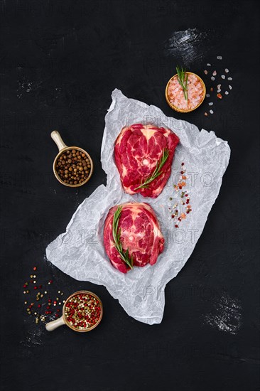 Fresh raw lamb neck on wrapping paper with herbs and seasoning