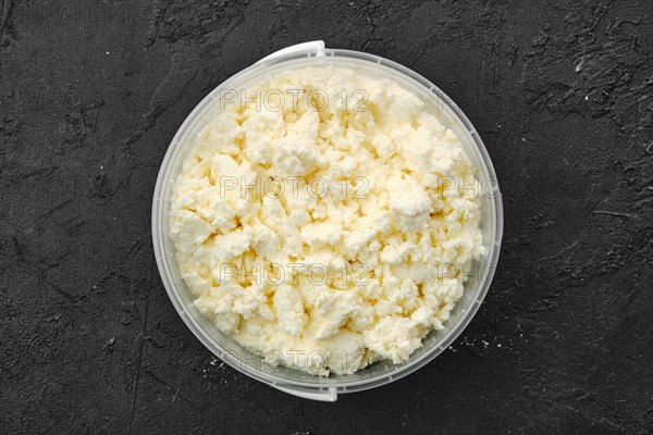 Top view of homemade cottage cheese in plastic bowl