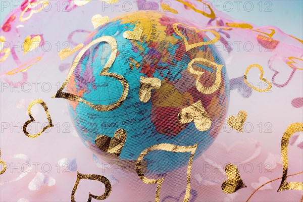 Little model globe under a fabric with heart patterns